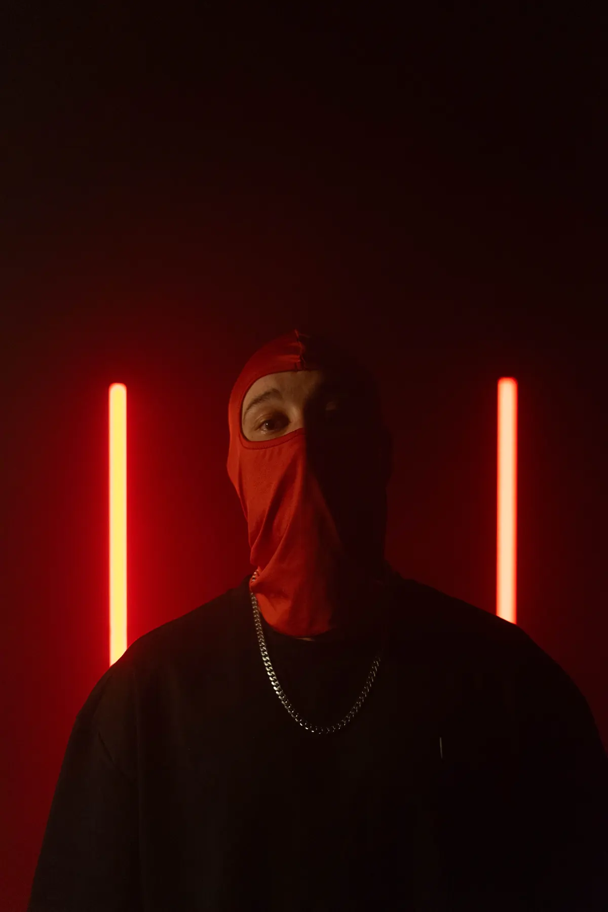 Retrato de ANTIK con pasamontañas rojo entre dos neones